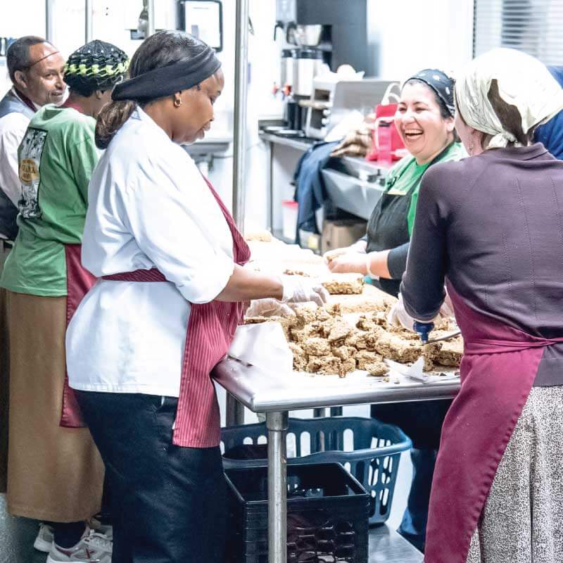 Beautiful Day Granola workers laughing and cooking together in a kitchen